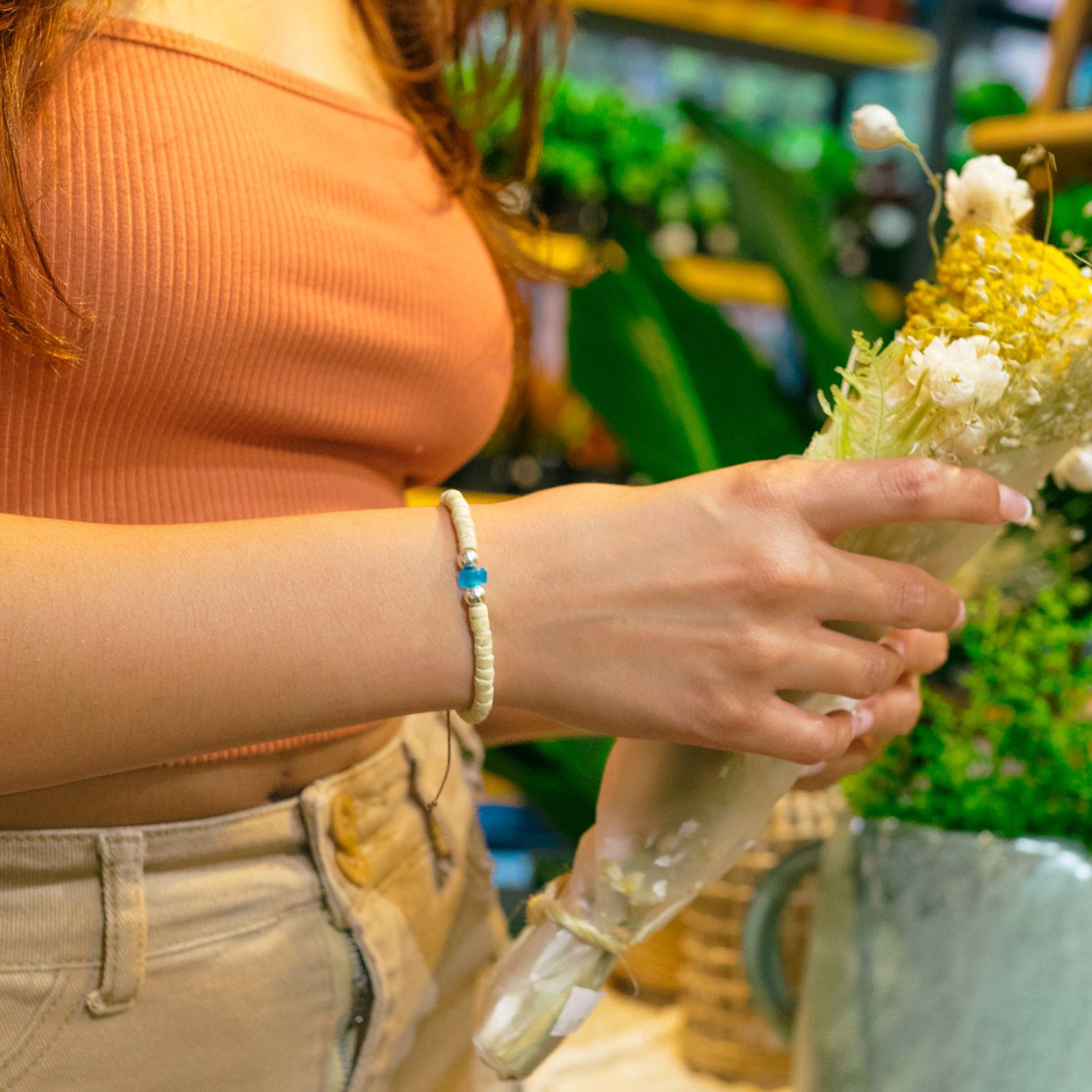 Woman bundling together flowers while wearing an EcoSea bracelet on her wrist